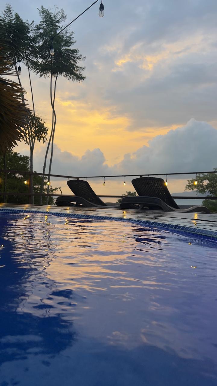Pool at dusk with loungers and string lights facing the ocean
