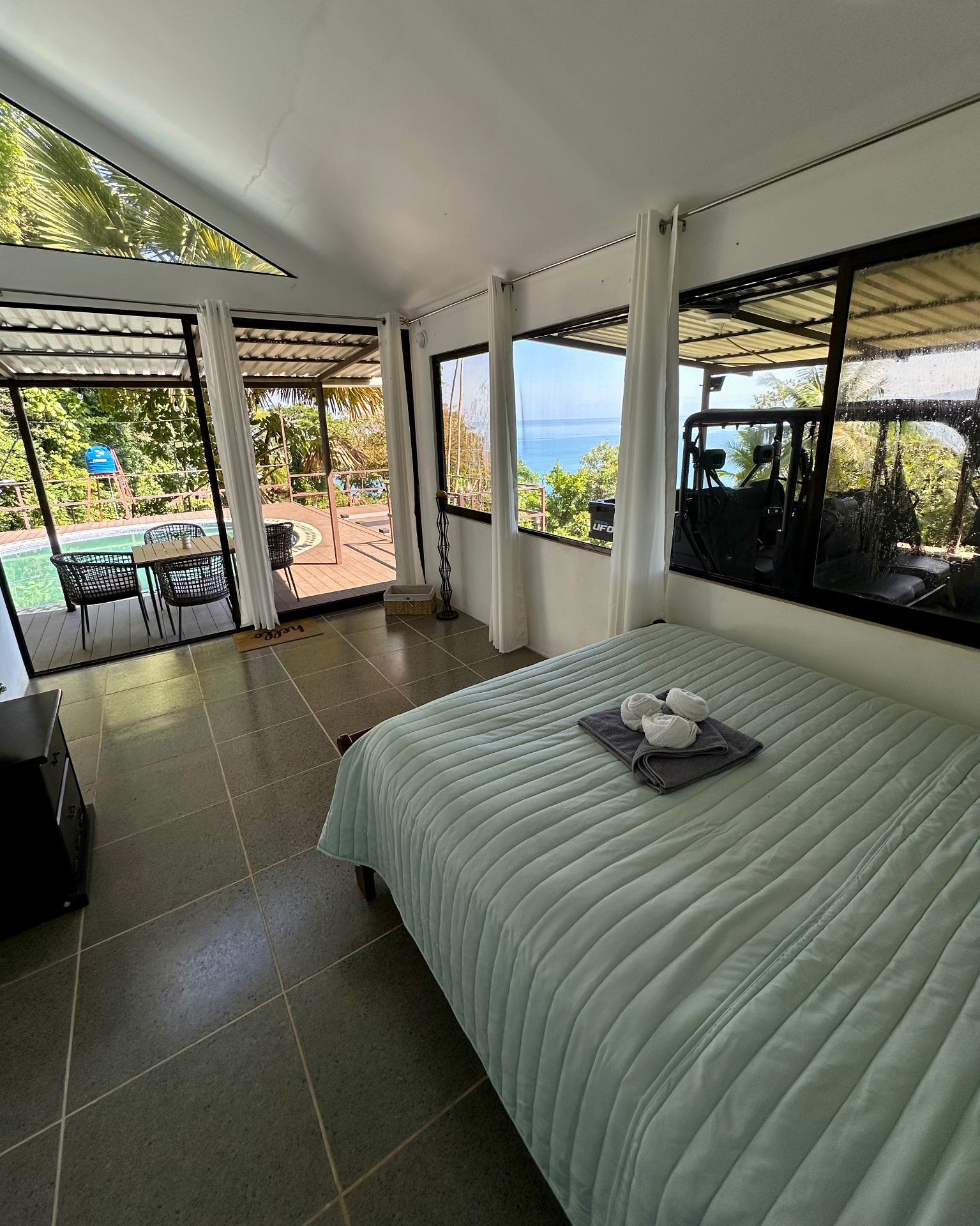 Habitación con cama y vista a la piscina y al mar